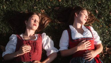 Two women in traditional European attire enjoying a peaceful moment in a grassy park in autumn.